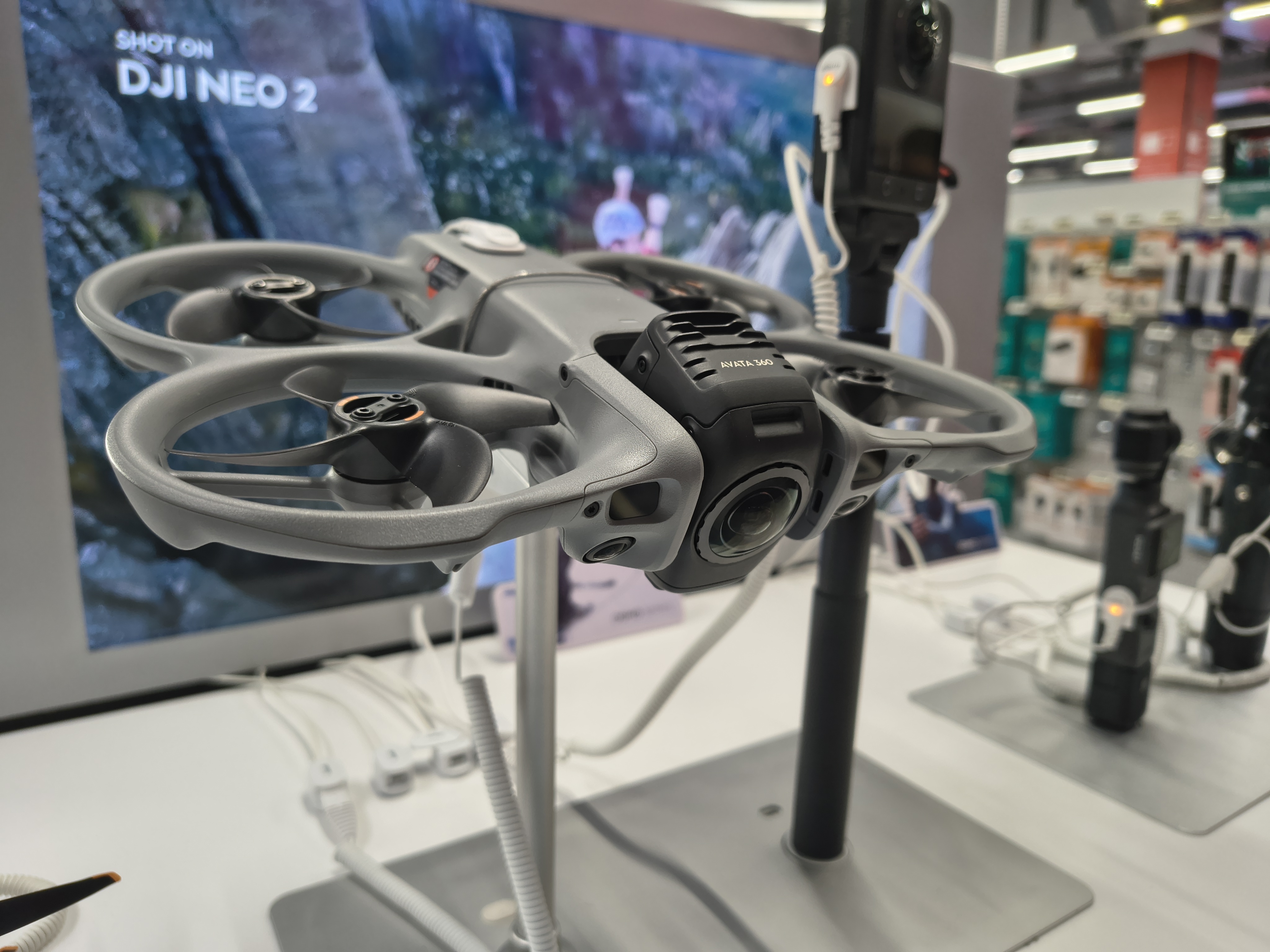 DJI Avata 360 drone on a retail display stand with camera and propeller guards visible