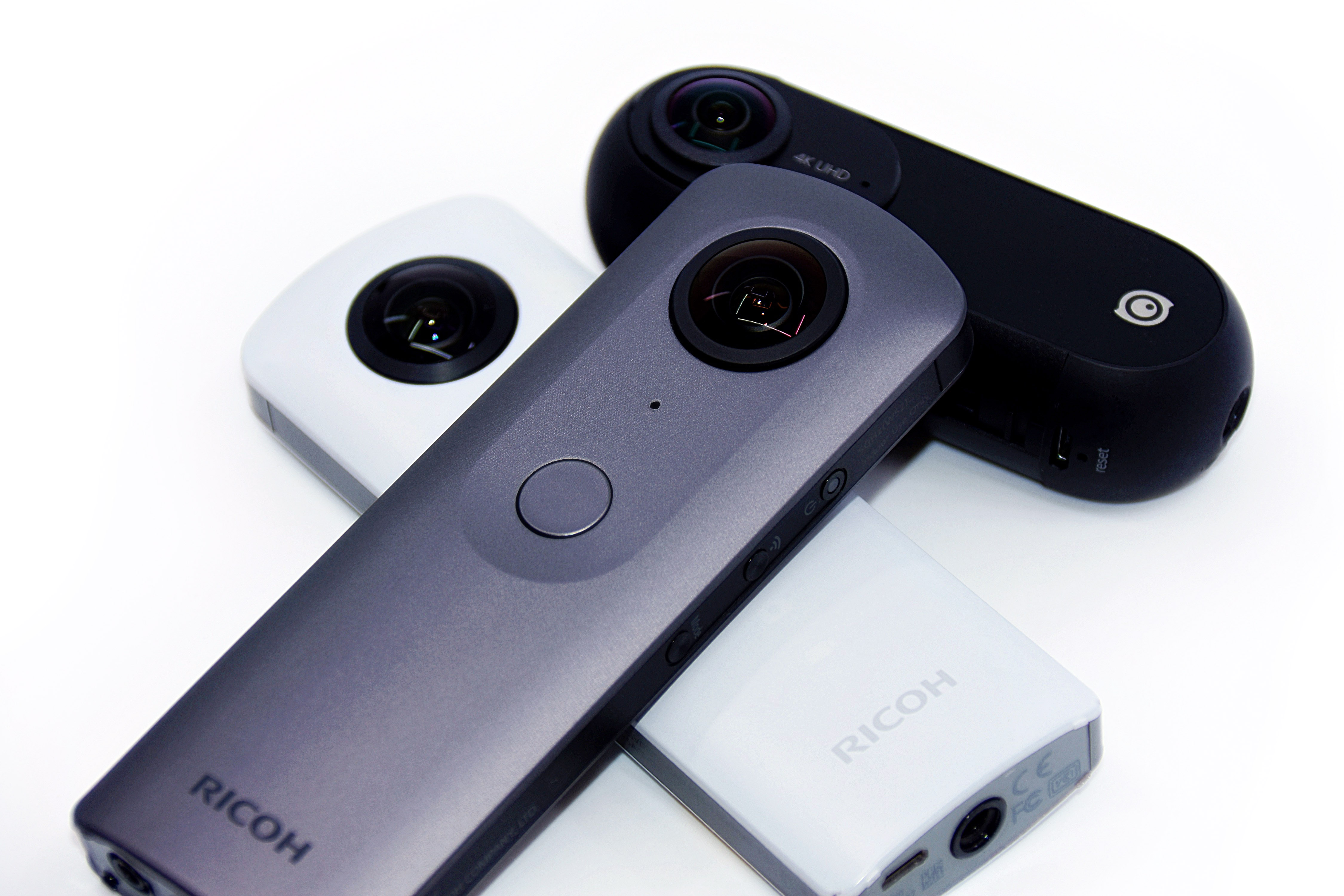 Black original Insta360 ONE at the rear right, behind a gray Ricoh Theta V and white Theta SC