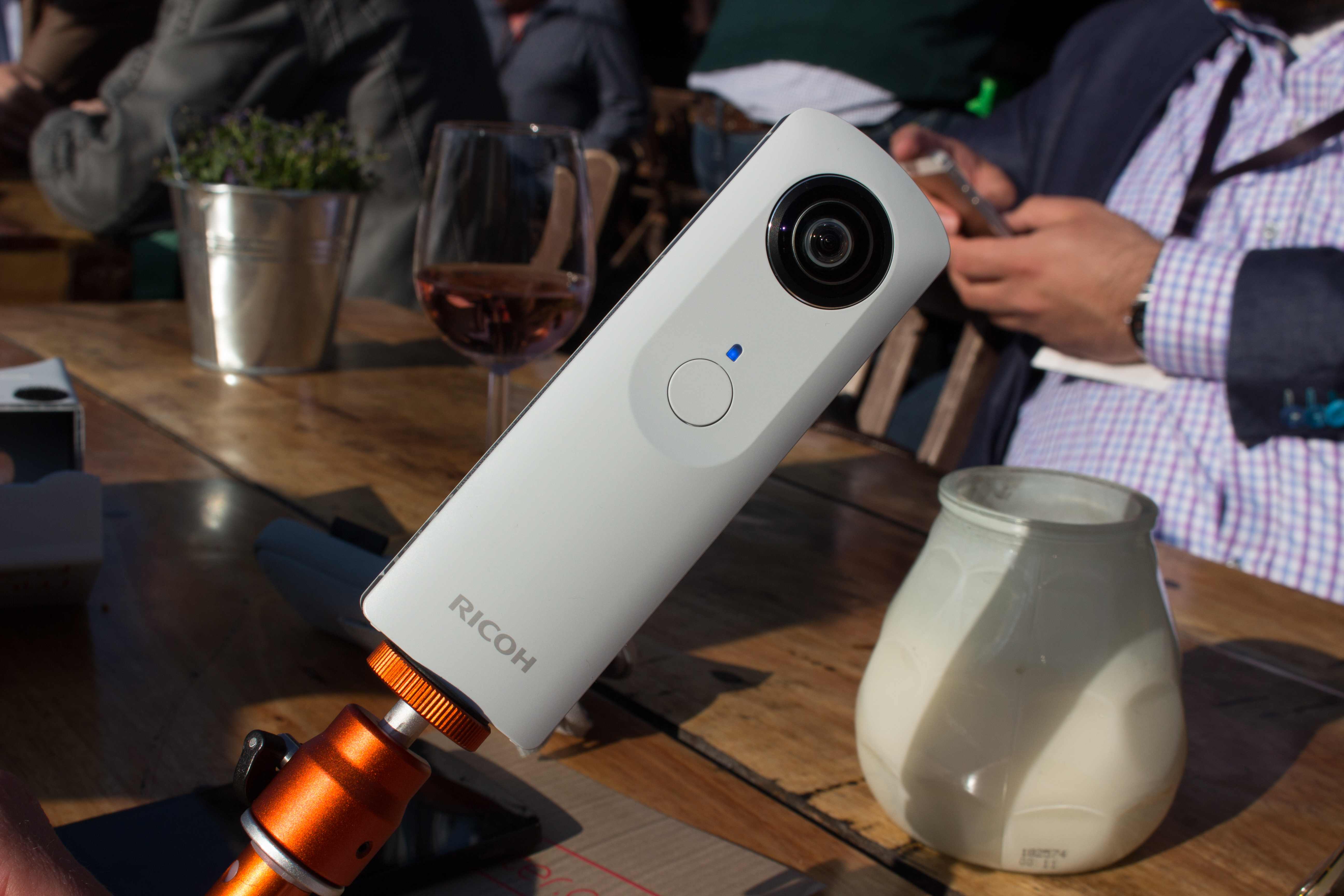 White Ricoh Theta m15 on an orange support beside a table at the 2015 TNW conference