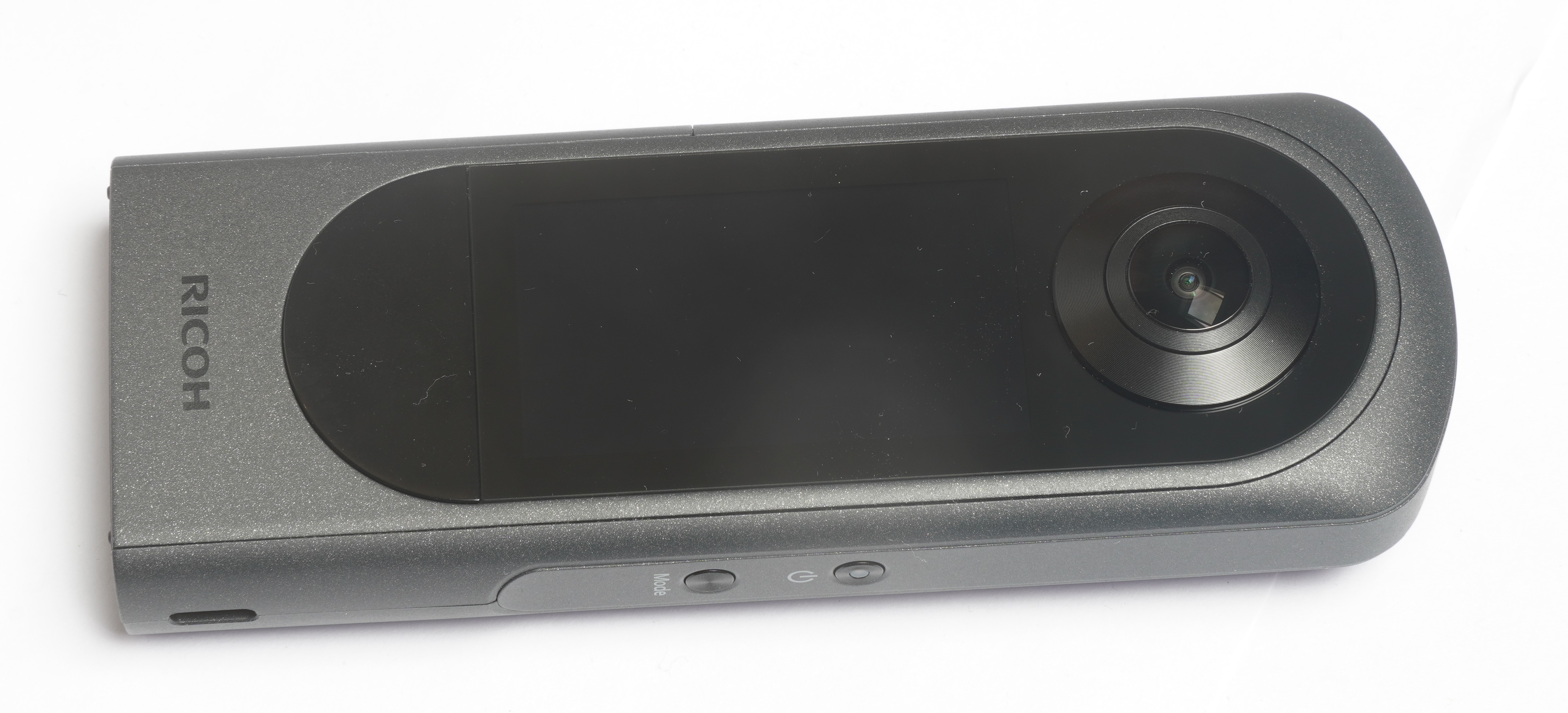 Ricoh Theta X showing the touchscreen face, lens and side controls