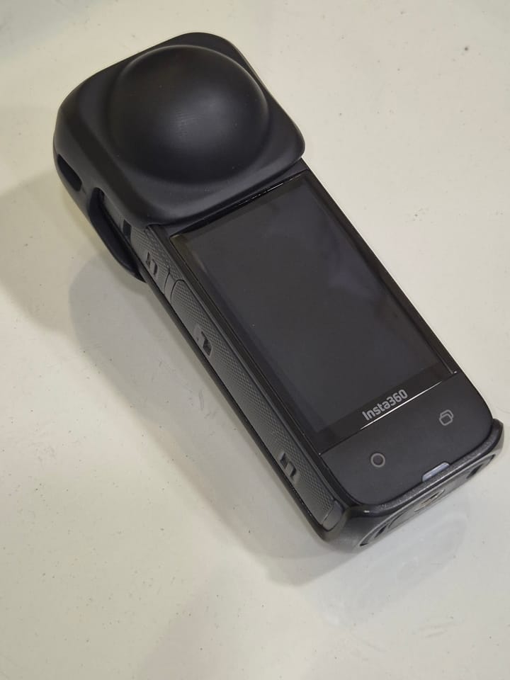 Insta360 X4 resting on a white surface with its lens cap fitted